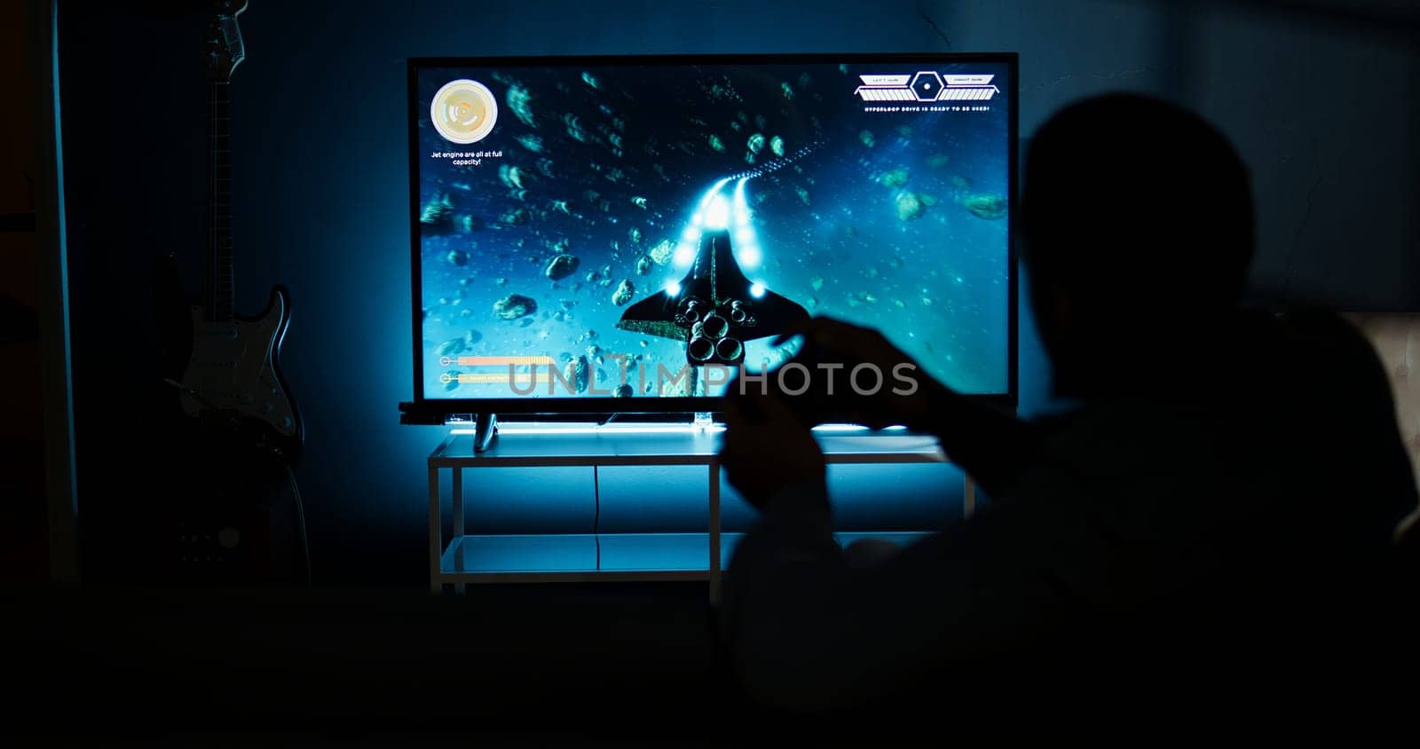 Young adult having fun with video games on his smart tv setup, connecting his console on lcd monitor television in living room and enjoying chill game night at home. African american gamer. Camera A.