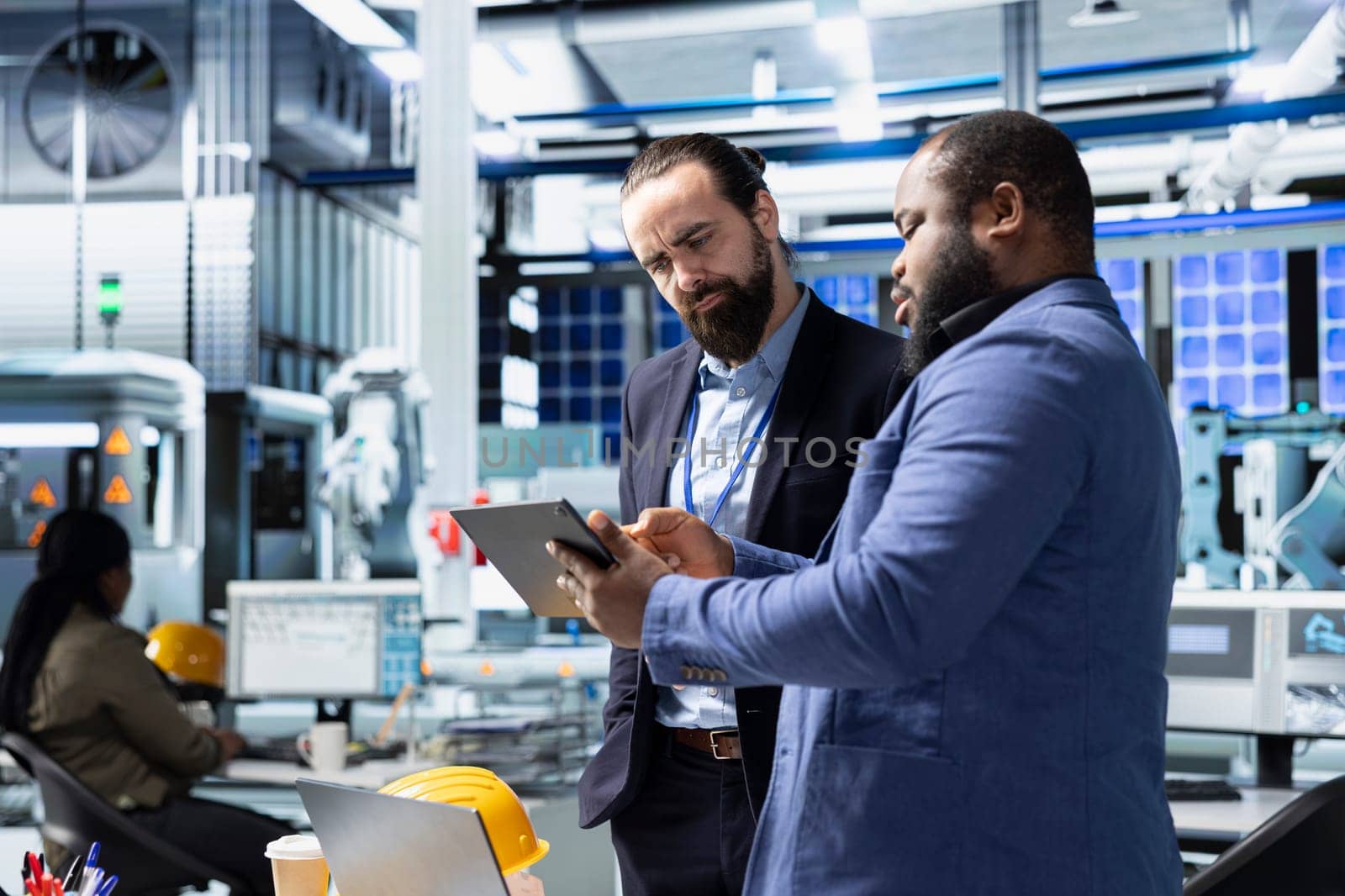 Multiethnic specialists engineers doing teamwork on modern production line for solar panels power, combining technical insight and collaboration for renewable energy infrastructure.