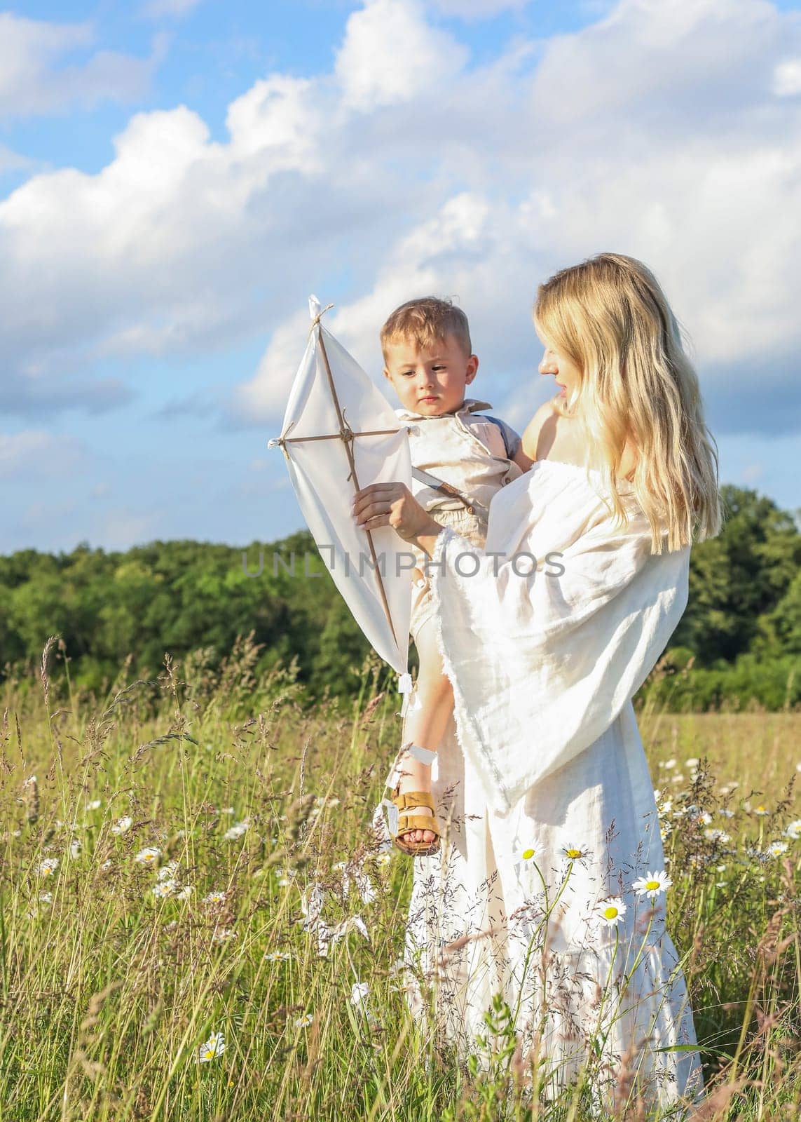A small child in his mother's arms, they are having fun in the meadow, flying a kite. High quality photo