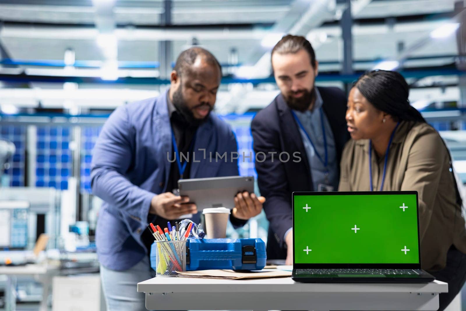 Team members in suits overseeing factory activity next to green screen, blending professionalism and technical expertise in the world of sustainable industrial energy. Cheaper power.