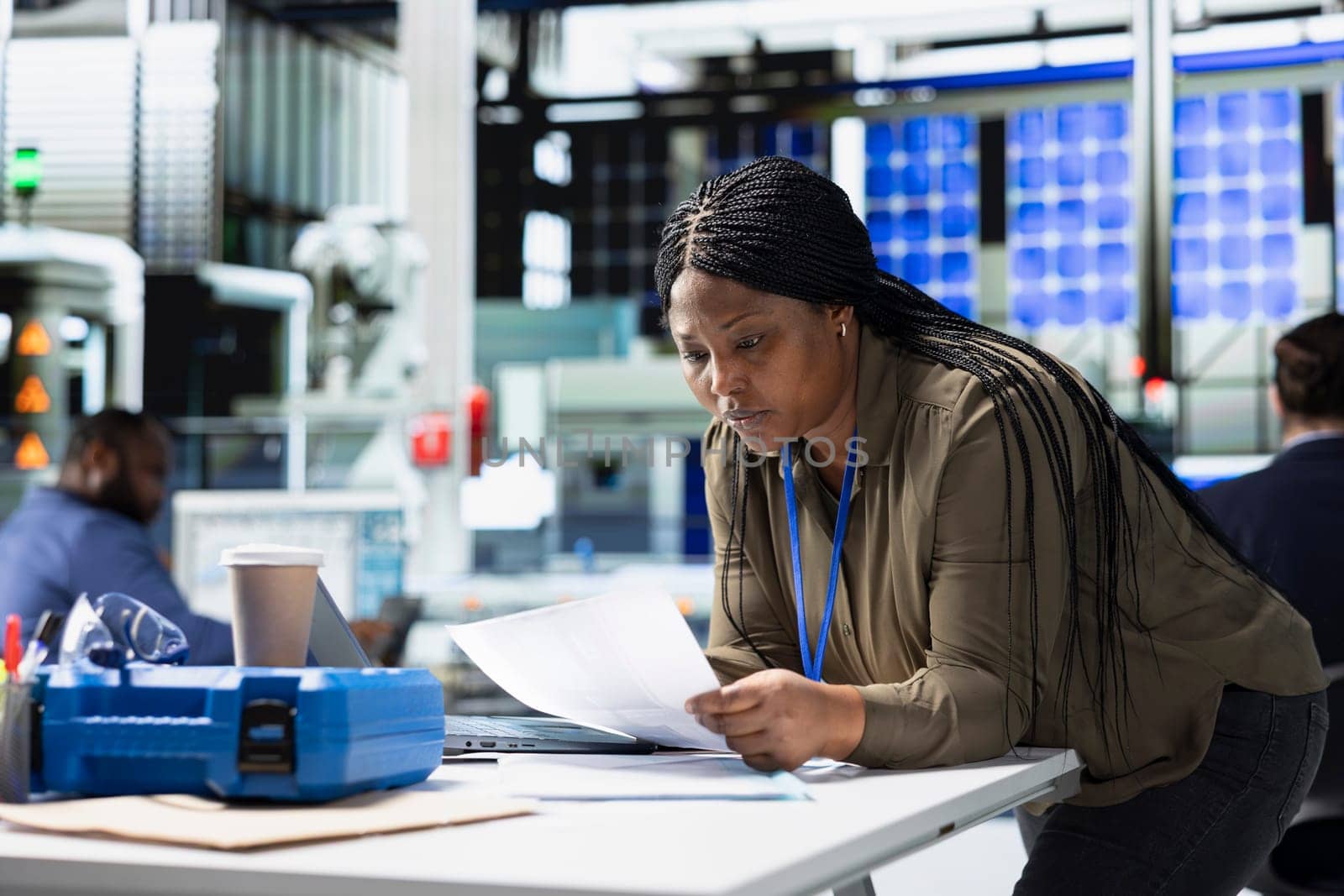 Woman master engineer reviewing production line data on papers, manages factory activity in a solar panel plant to ensure effective quality control and commitment to renewable energy tech.