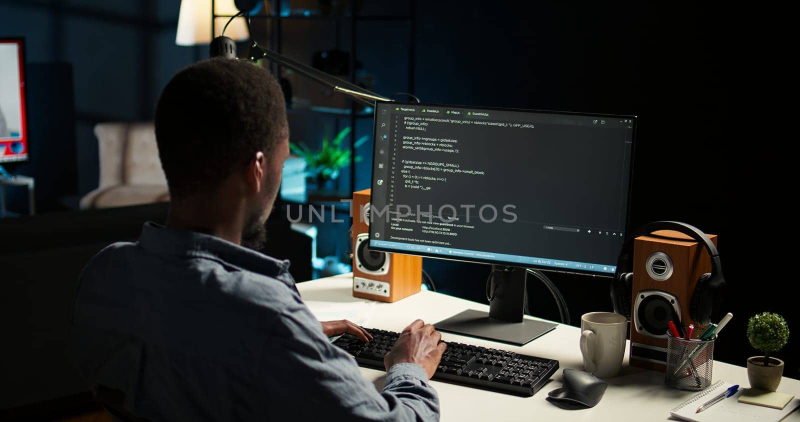 African american expert at desk using pc for programming and data analysis. Young networking expert working from his home setup, manages information technology and data center. Camera A.