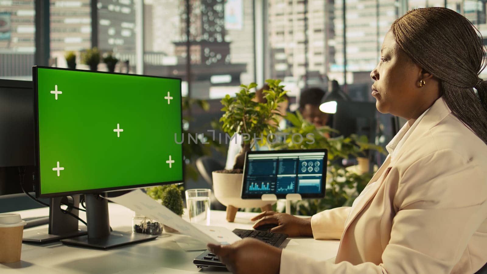Employee at work using isolated screen PC display to finish project tasks. African american office clerk in workplace reading data statistics on mockup computer monitor, camera B