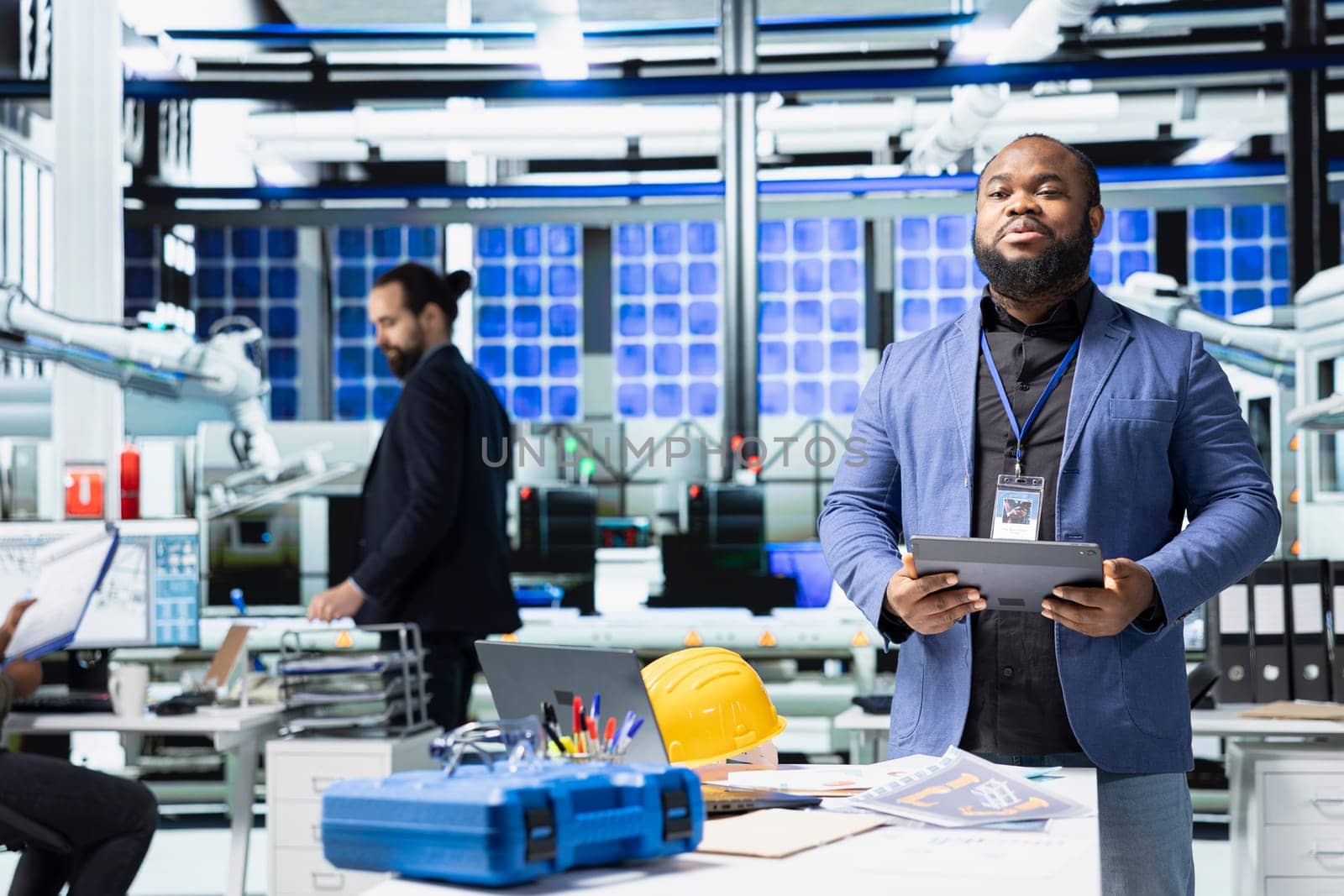 African american supervisor talking to his coworkers and associates in a meeting, sharing insight on the assembly and production line. Reviewing sustainable solutions for energy industry.