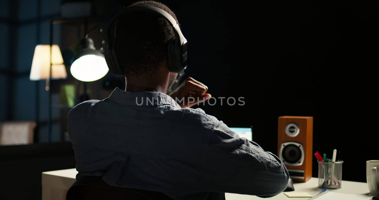 African american analyst works on accounting analysis while he is dancing, feeling the rhythm and checks financial balance. Remote worker listening to favorite groovy music on headphones. Camera A.