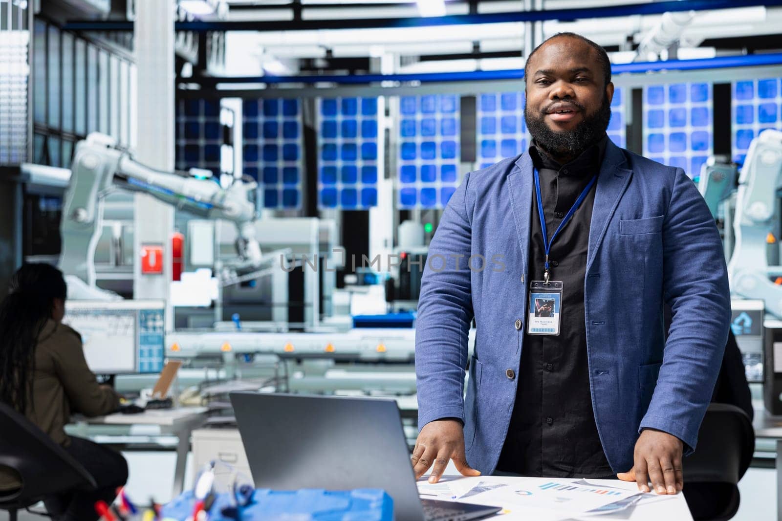 Black industrial engineer in a solar panel plant assesses system performance, playing a crucial role in monitoring efficiency and workplace safety. Renewable power with photovoltaics.