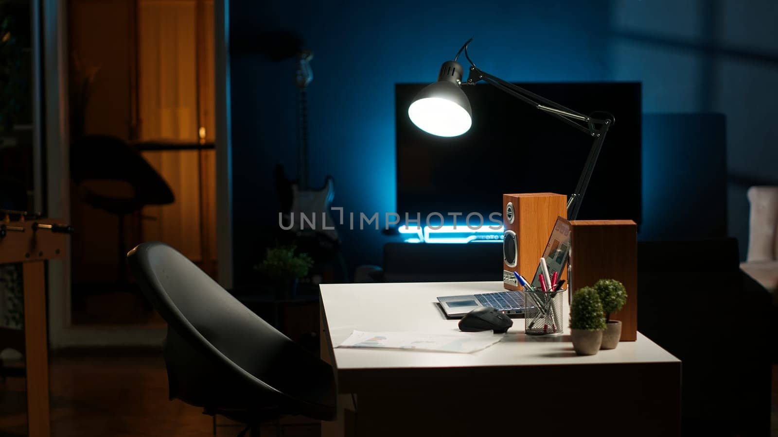 Modern home office in a stylish apartment with wooden furniture and cozy decorations, urban loft. House plants, a smart TV and a creative workspace with a desk setup for a comfortable lifestyle.