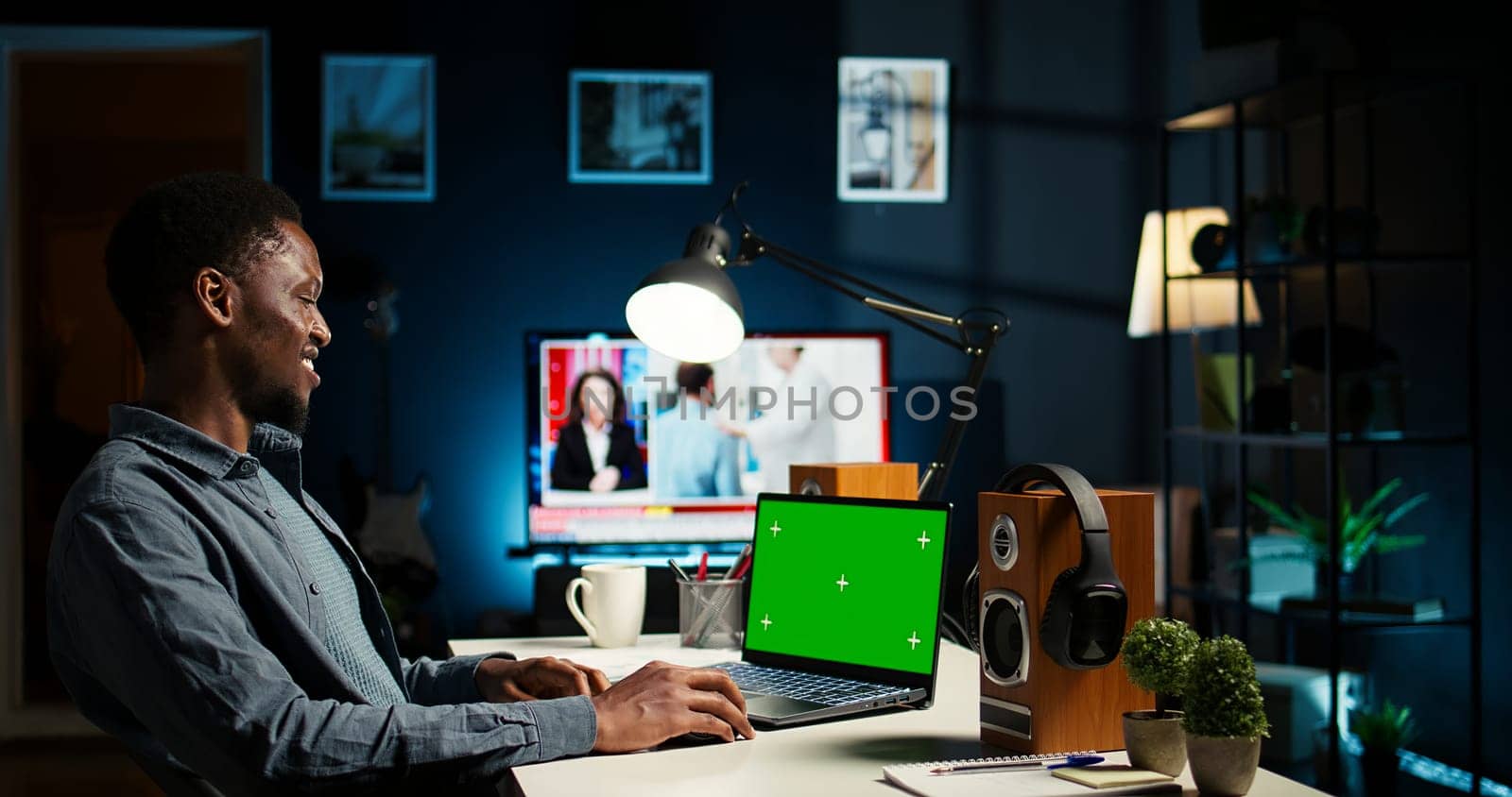 African american man working from home with green screen on laptop, looking at data on the web. Remote worker in personal apartment office crosschecking important info. Camera A.