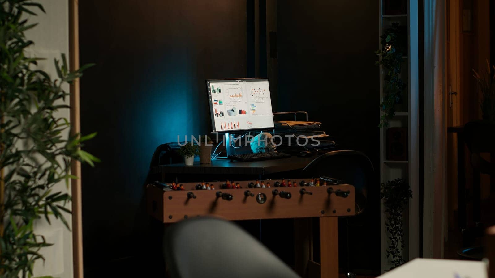 Cozy loft style illuminated apartment with a modern home office. The space features wooden furniture, decorative plants and a TV combining stylish interior design with functional workspace.