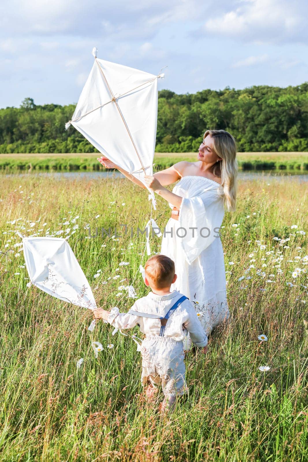 Beautiful young mother and child flying a kite in the meadow. High quality photo
