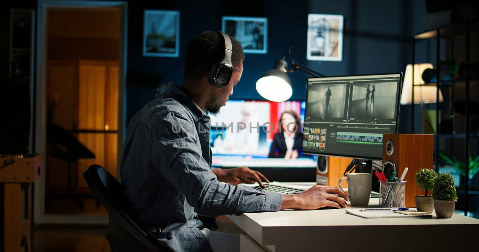 Focused male editor working on video montage in a creative software at home office setup, digital media content. Filmmaker using dual monitors to edit footage in post production. Camera A.