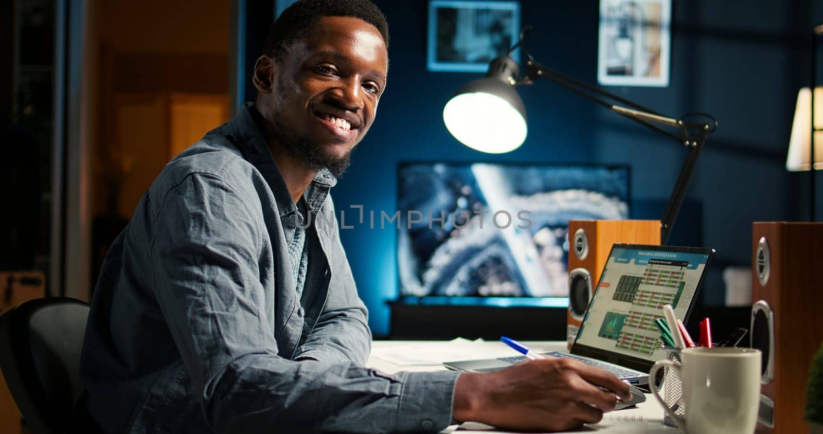 African American freelancer working from home writing notes and researching data driven topics. Focused on productivity and planning tasks in a modern apartment for remote work success. Camera A.