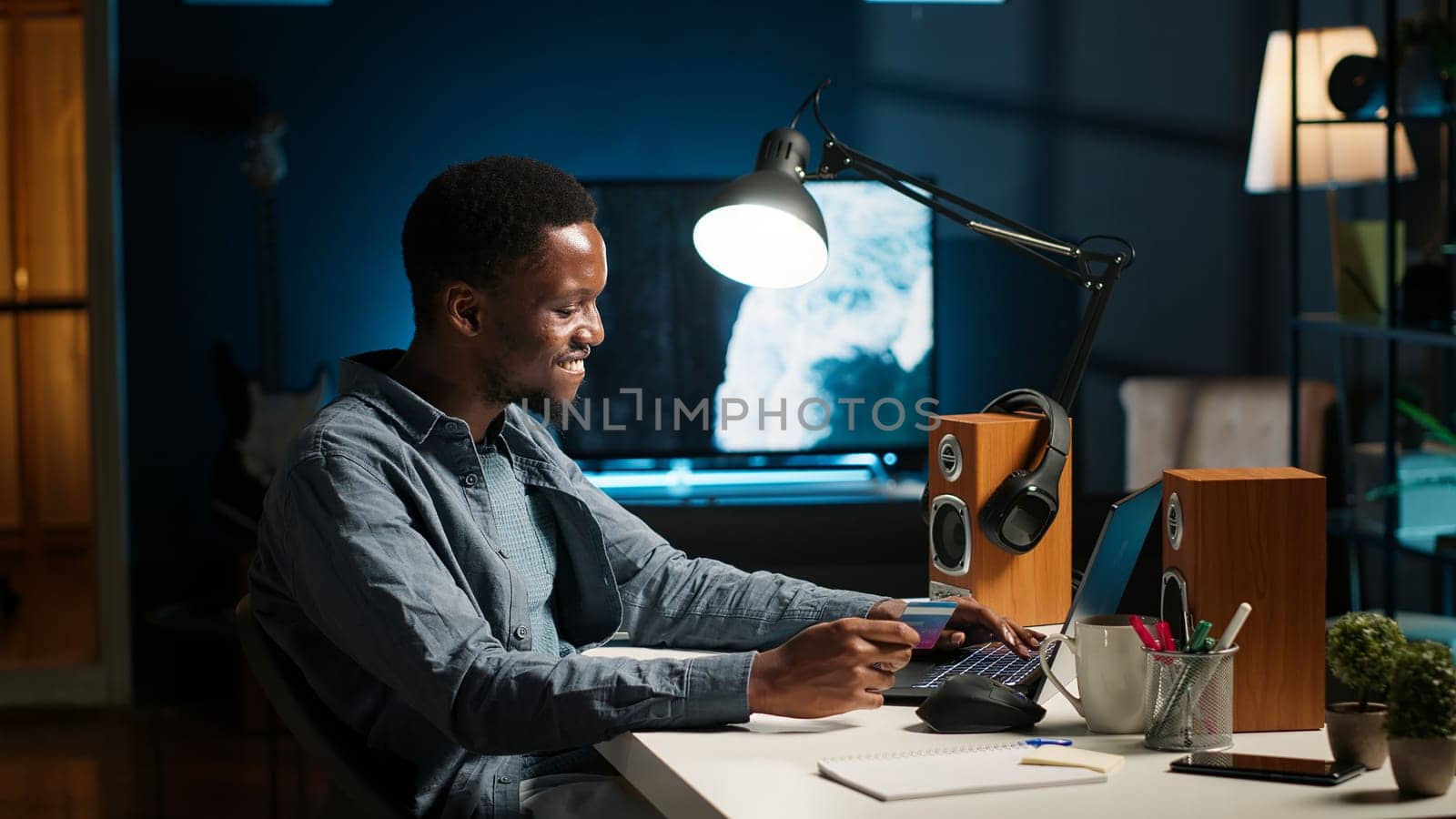 African american guy entering credit card details on internet page, preparing to pay on online clothes shop. During shopping spree on laptop, young man accepts digital monetary transaction. Camera B.