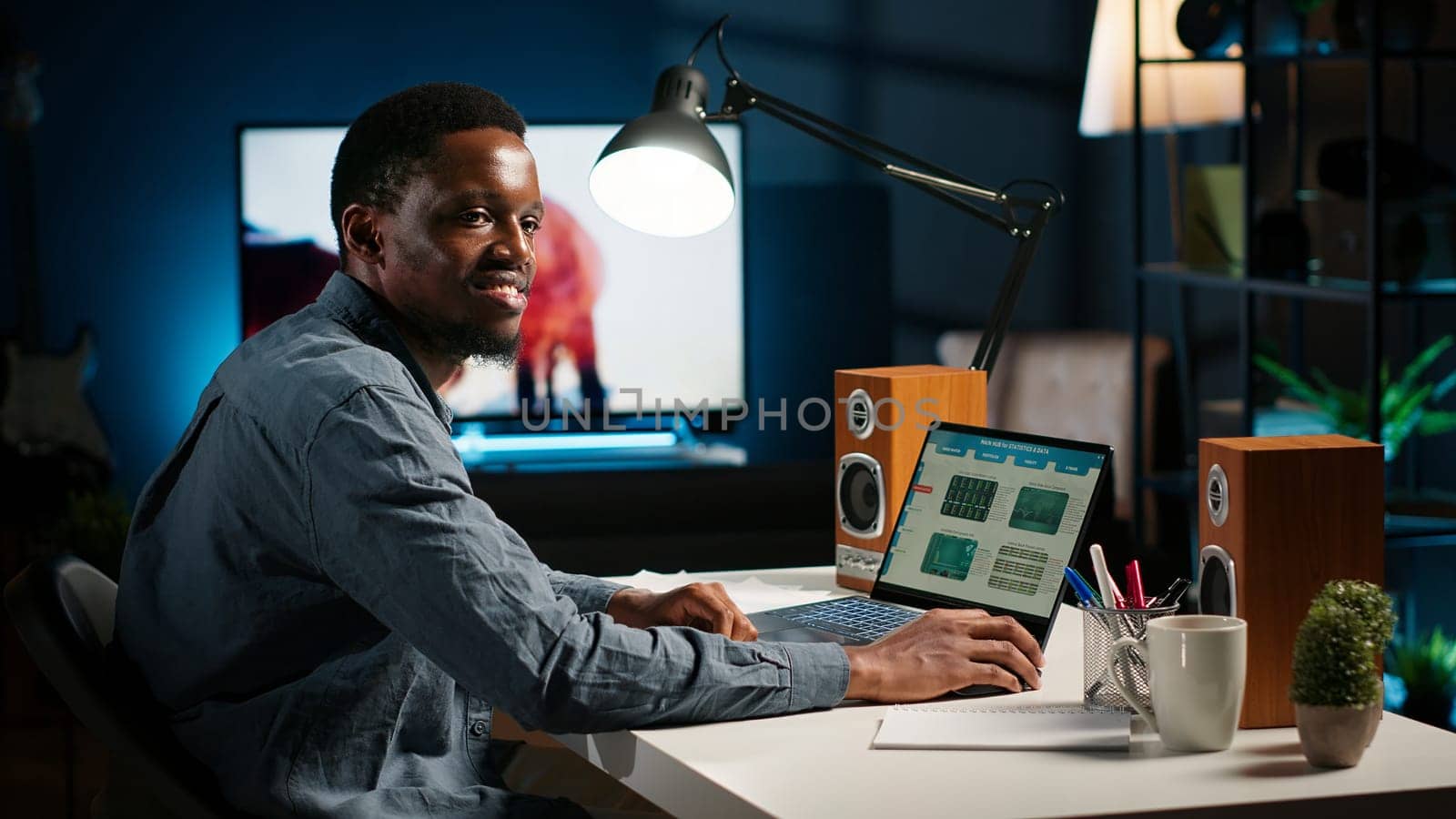 Black accountant working on monthly revenue balance on laptop at home, calculating investment money to double the profit. Economist looks into legal trade statistics, supply and demand. Camera B.