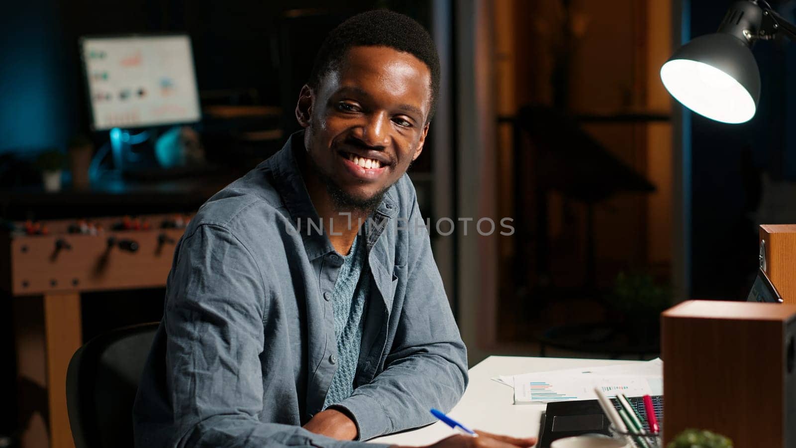 African American freelancer working from home writing notes and researching data driven topics. Focused on productivity and planning tasks in a modern apartment for remote work success. Camera B.