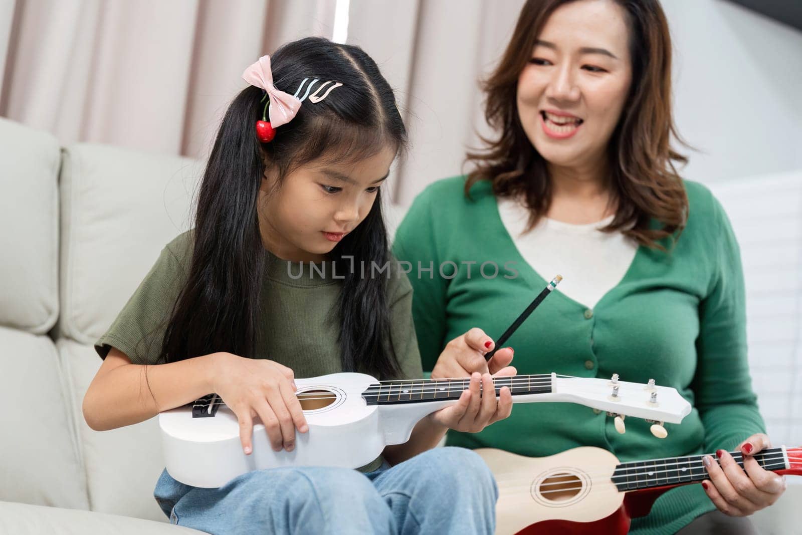 A joyful moment between a mother and daughter as they explore music together, fostering creativity and connection through ukulele lessons.