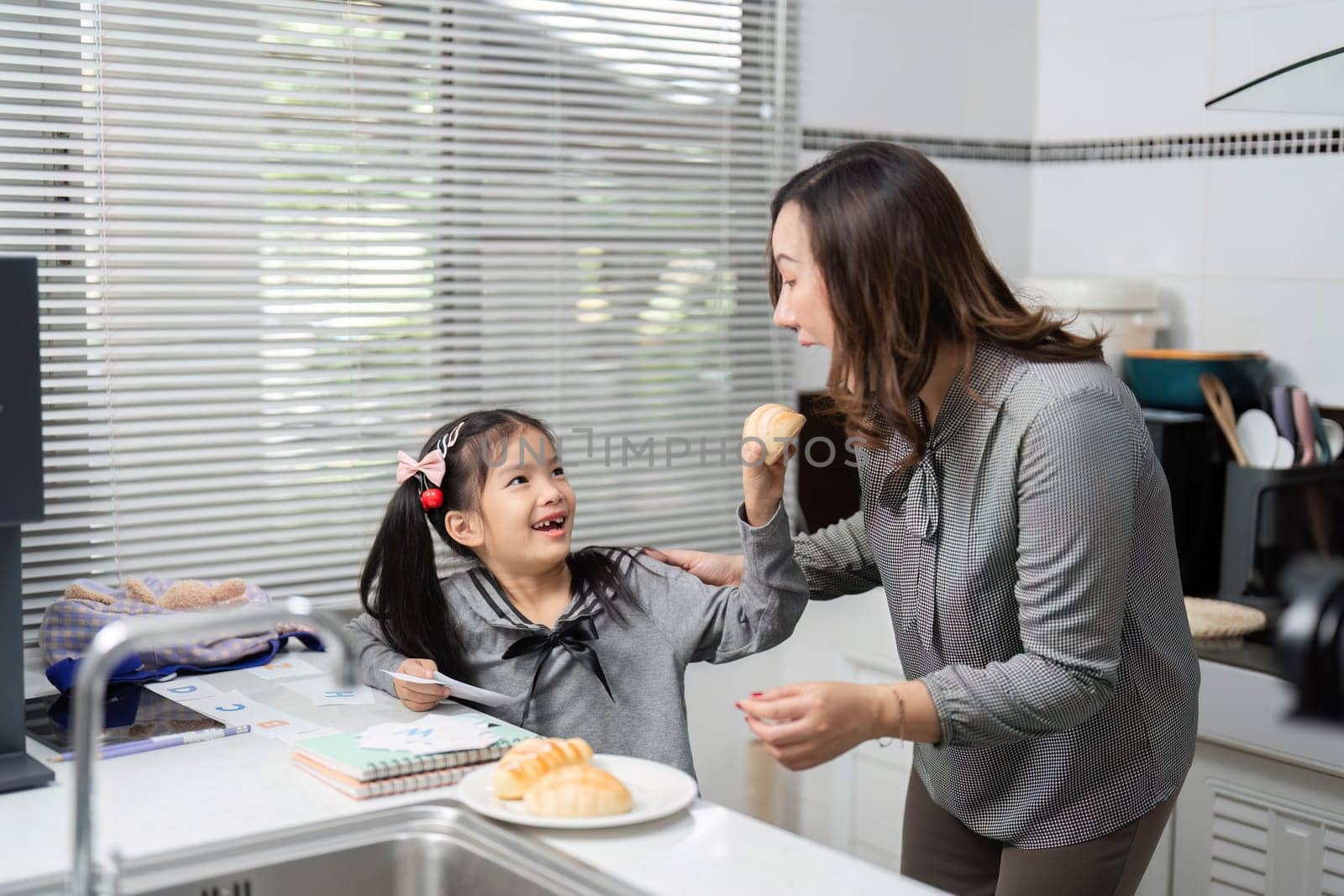 A joyful interaction between a mother and her daughter as they enjoy a tasty treat together in their cozy kitchen.