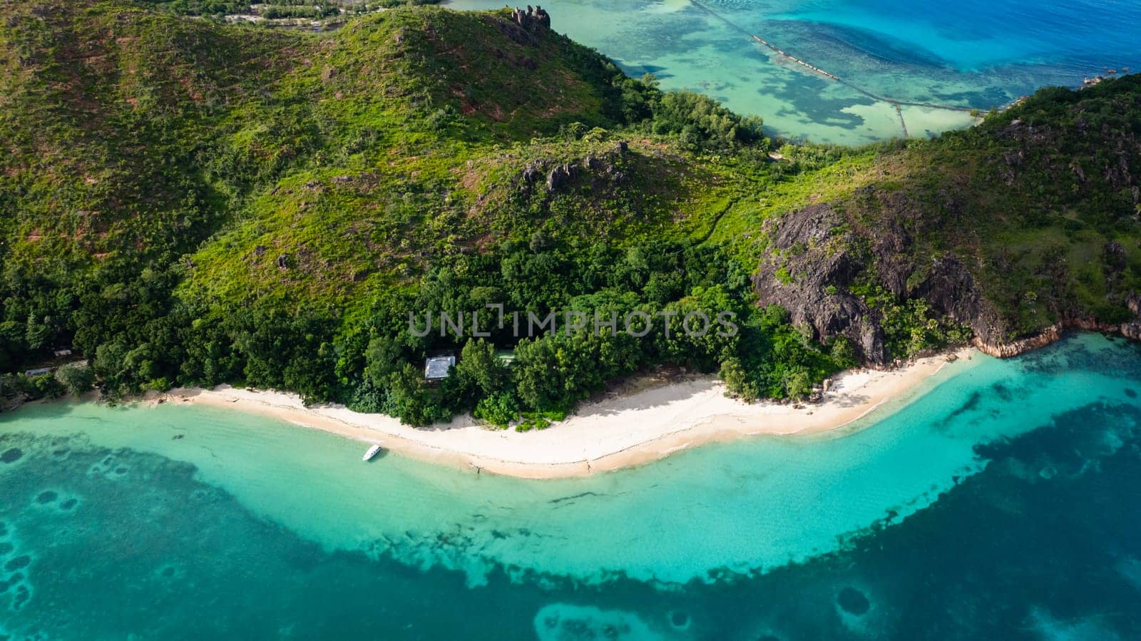 A hidden tropical beach surrounded by dense green hills and turquoise waters. Curieuse, Seychelles.