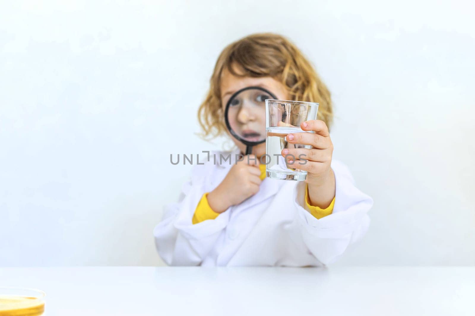 A child examines water with a magnifying glass. Selective focus. kid.