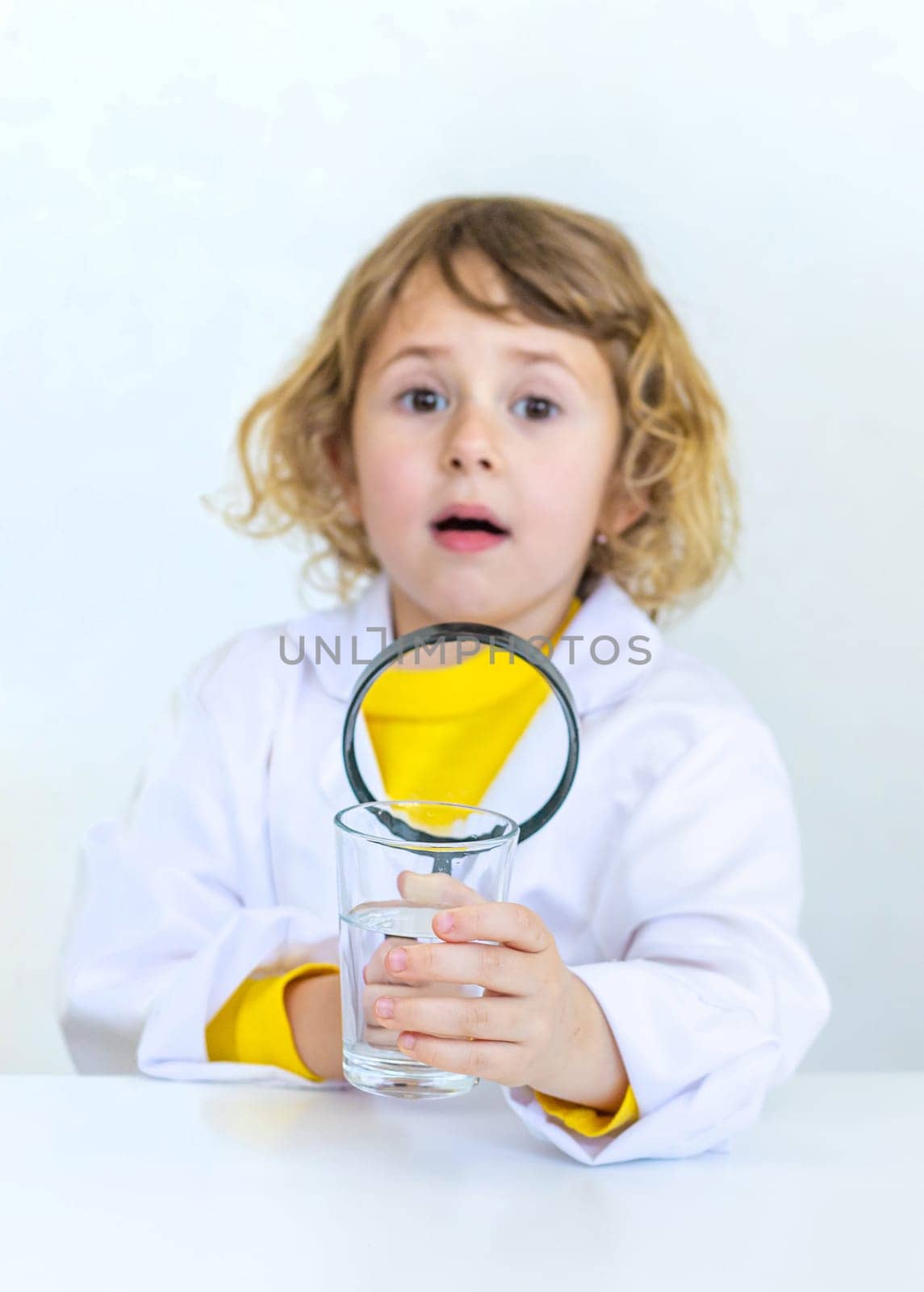 A child examines water with a magnifying glass. Selective focus. kid.