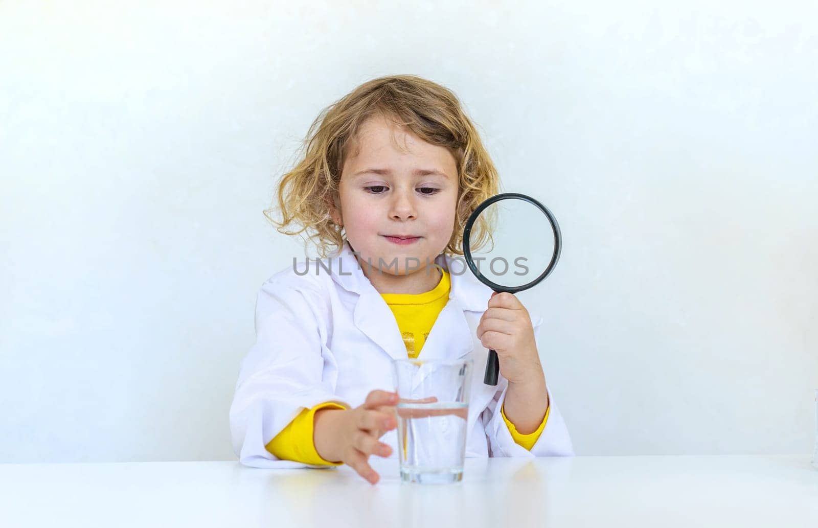 A child examines water with a magnifying glass. Selective focus. kid.
