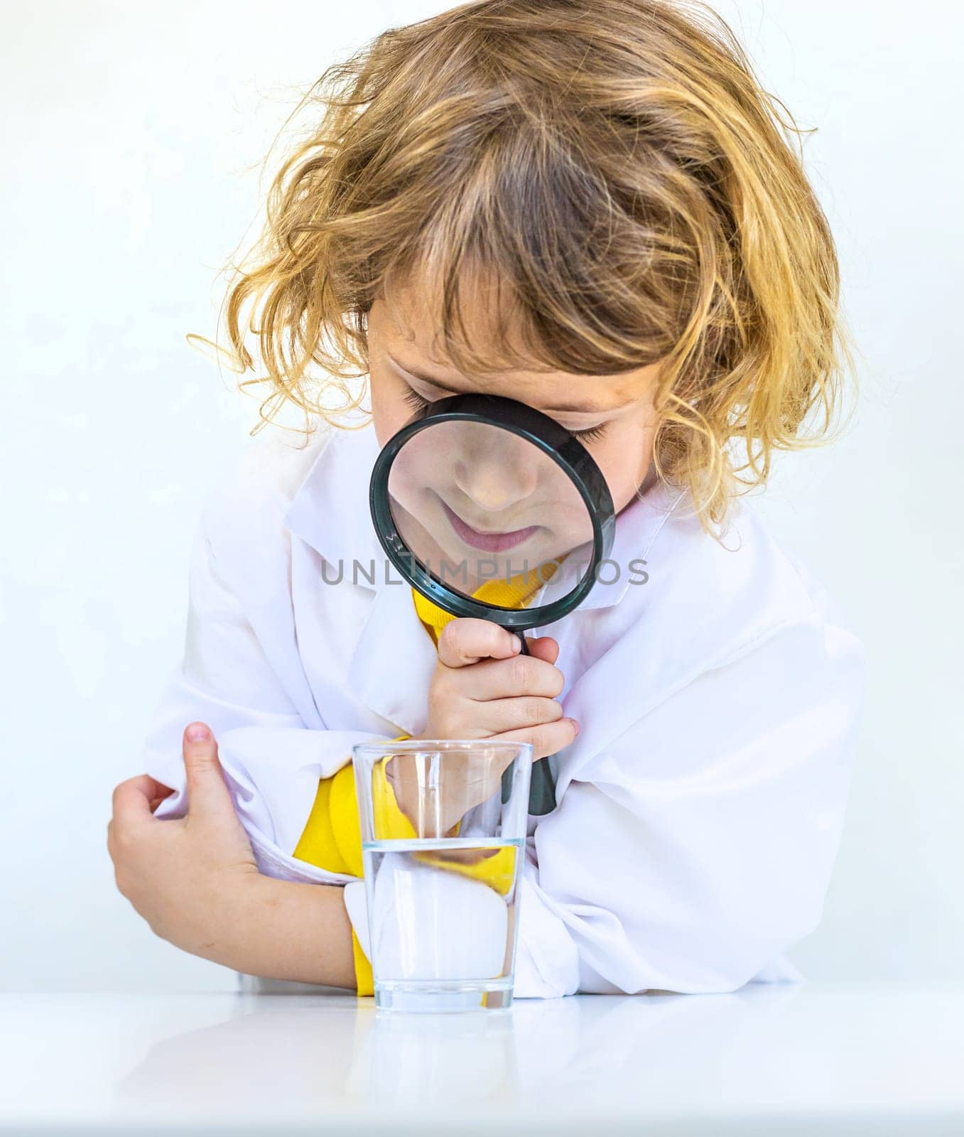 A child examines water with a magnifying glass. Selective focus. kid.