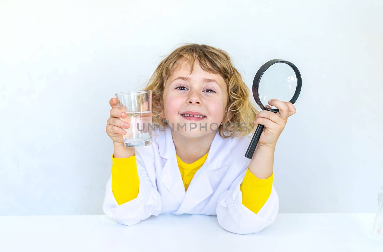 A child examines water with a magnifying glass. Selective focus. kid.