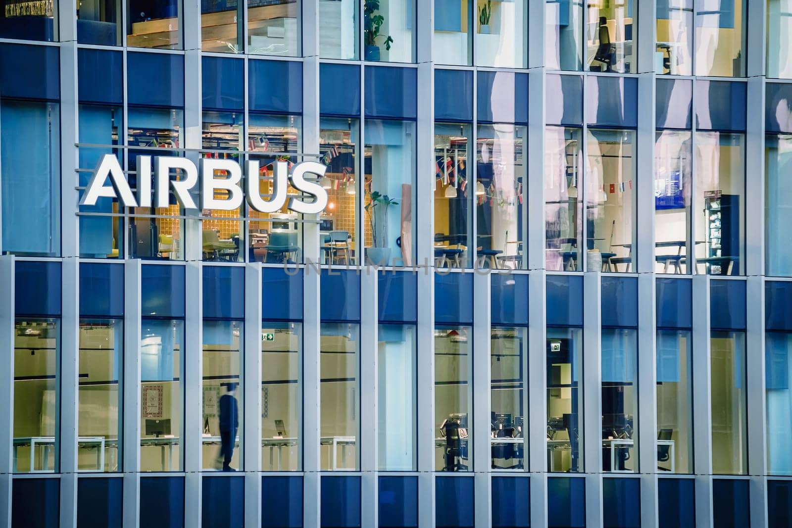 Jan 16, 2025 - Lisbon, Portugal: Day view of the Airbus office building or headquaters with bright illuminated logo and modern glass facade. Interior of workspace with people at desks, leading aerospace company, modern architecture, daily corporate