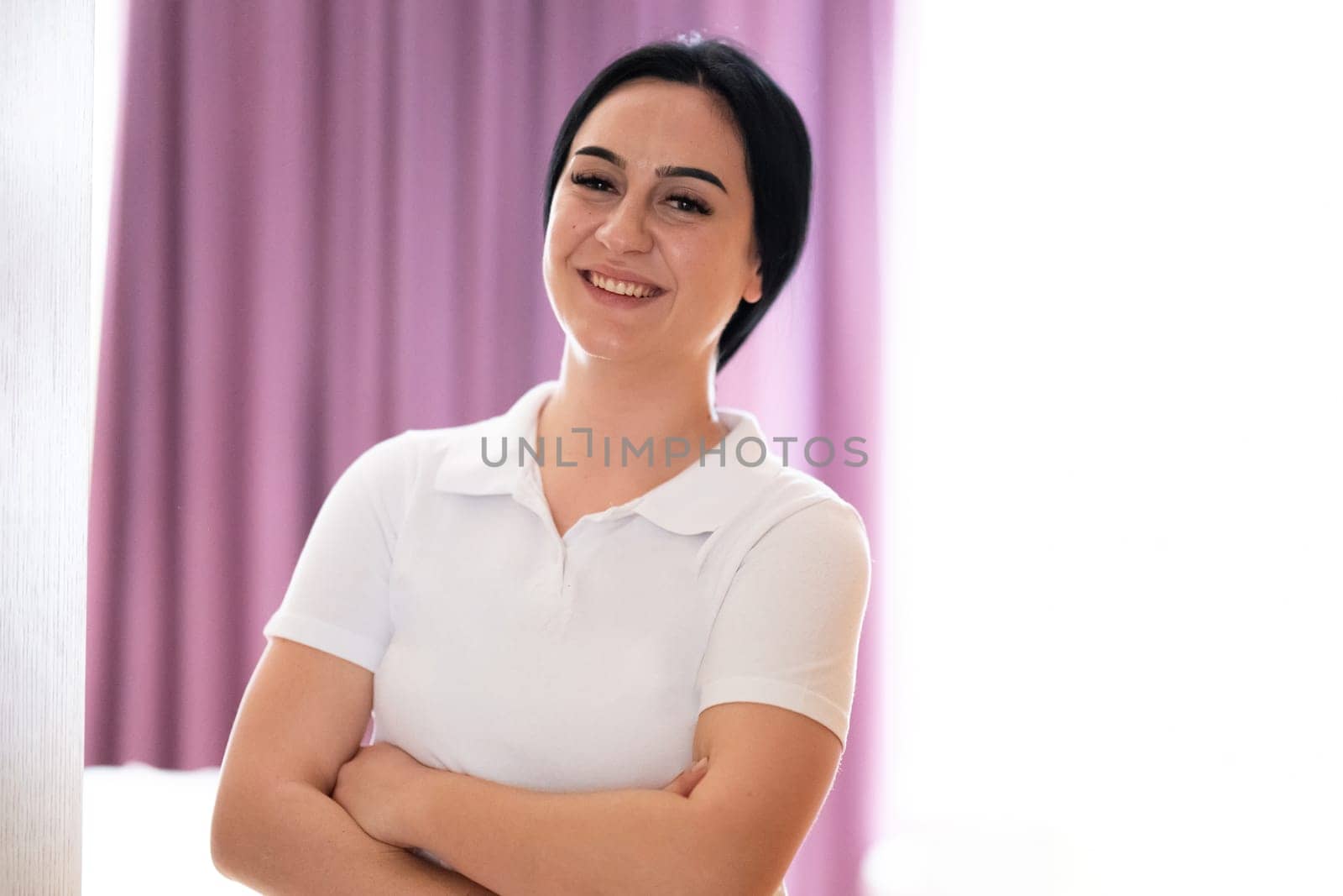 Confident Female Healthcare Worker. Portrait of a confident young female healthcare worker in a white uniform standing with arms crossed.