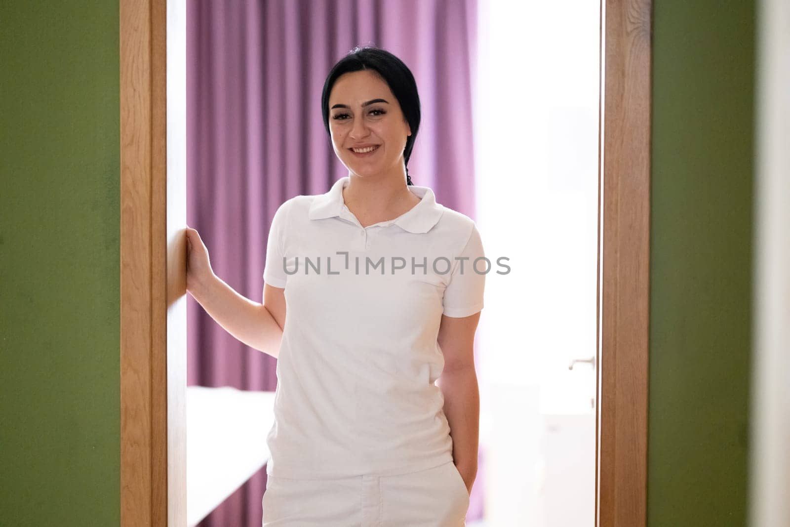 Female Therapist Smiling at Doorway. A female therapist stands at the doorway, smiling warmly, ready to welcome the next patient.