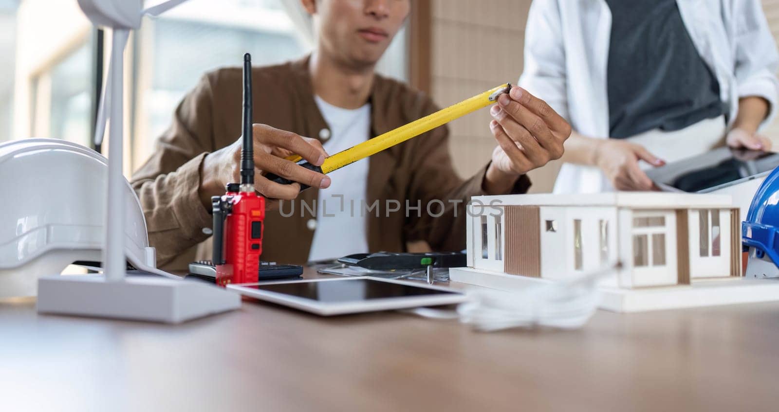 An architect measures materials while discussing sustainable building practices, emphasizing ESG and innovation.
