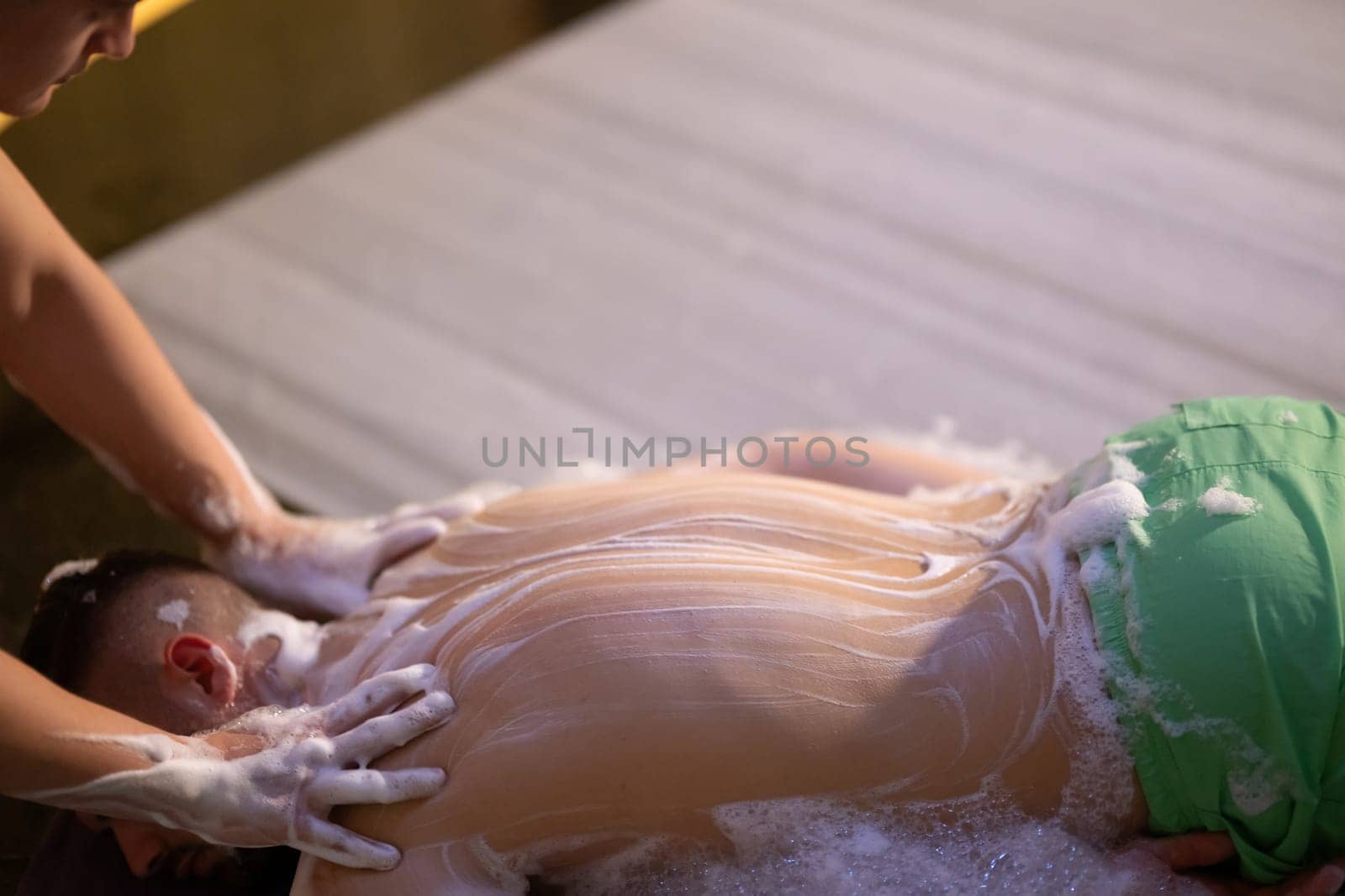 Back Massage with Foam. Therapist applies soap foam with htheir ands on patients back during traditional bath ritual