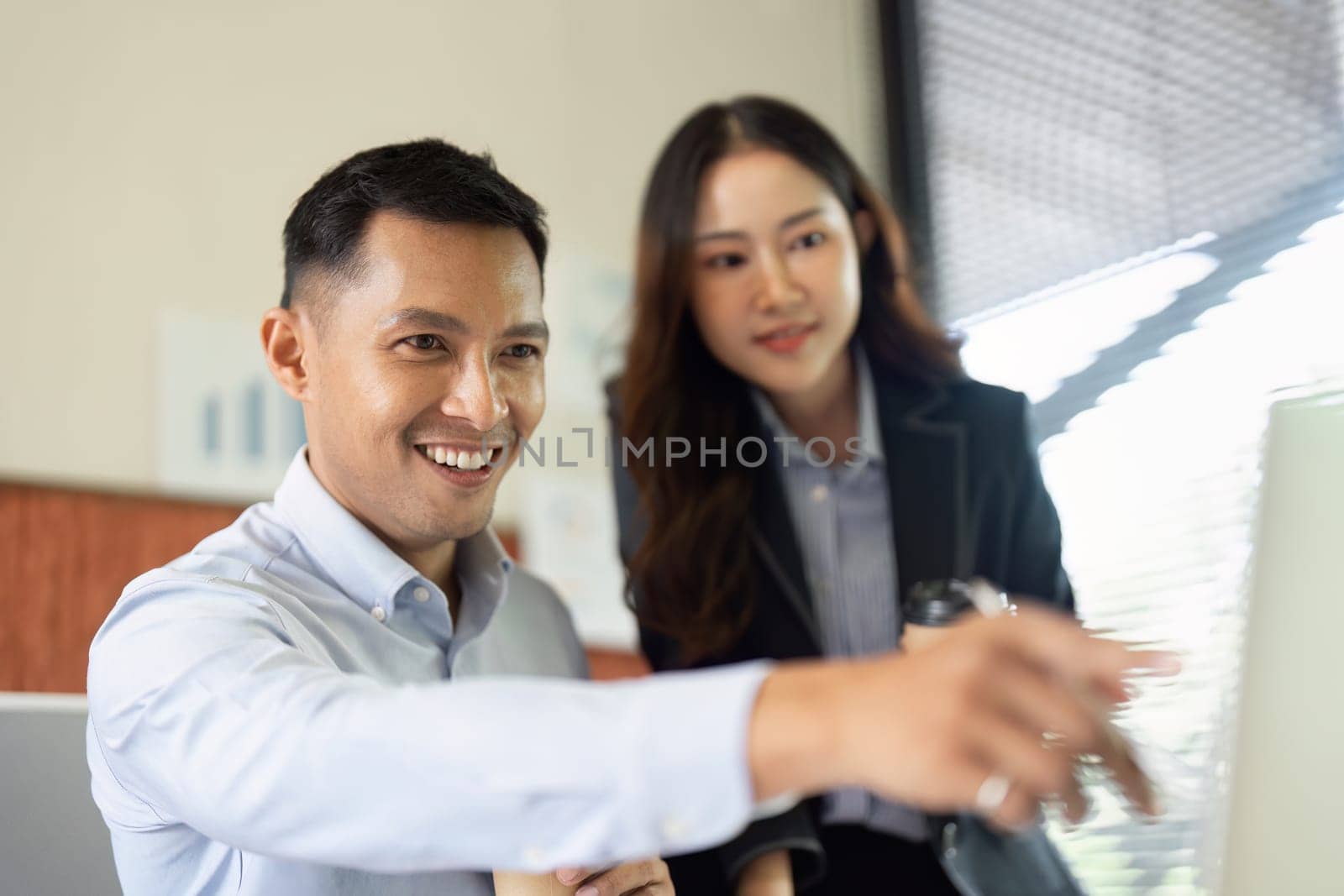 Two colleagues engage in a productive discussion at their desks, highlighting teamwork and innovation in a modern workspace.