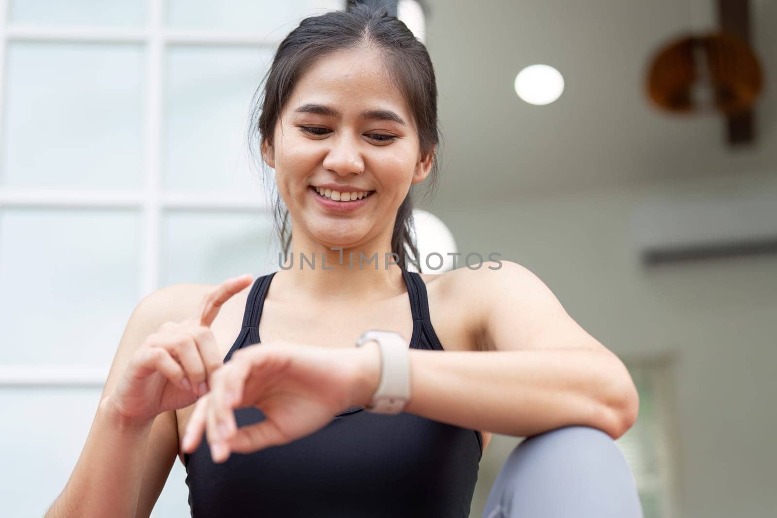 A young woman examines her smartwatch in a peaceful outdoor setting, highlighting fitness and wellness.