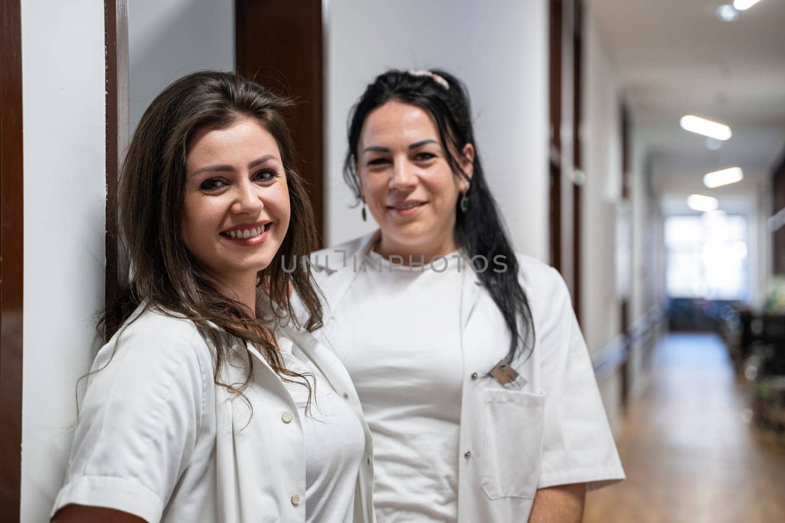 Two nurses take a well deserved break in the hospital hallway, resting after a long and demanding day of patient care