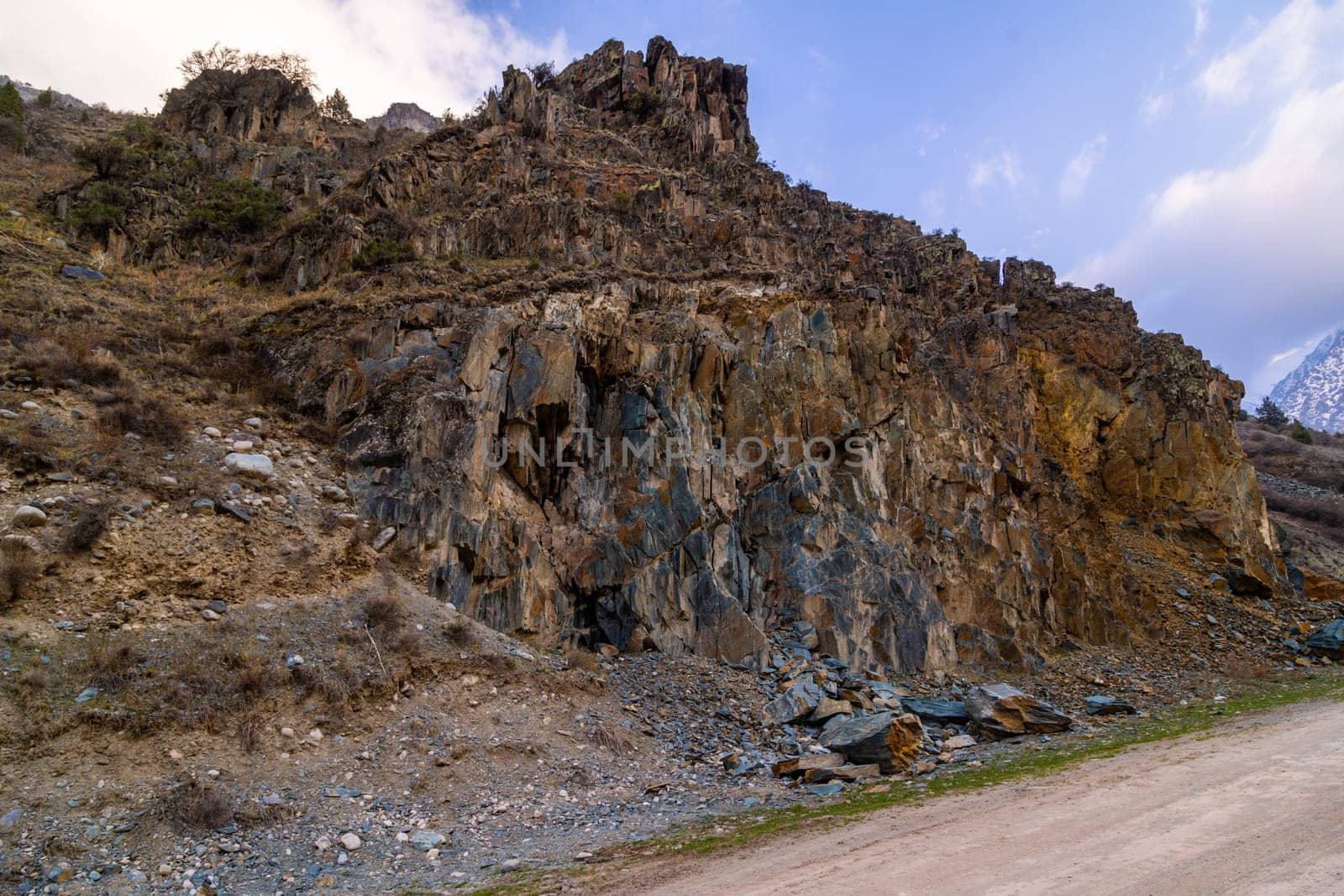 Majestic sedimentary rock formation towers above serene mountainous landscape. Natural beauty creates a rugged and dramatic atmosphere during daytime with clear skies.