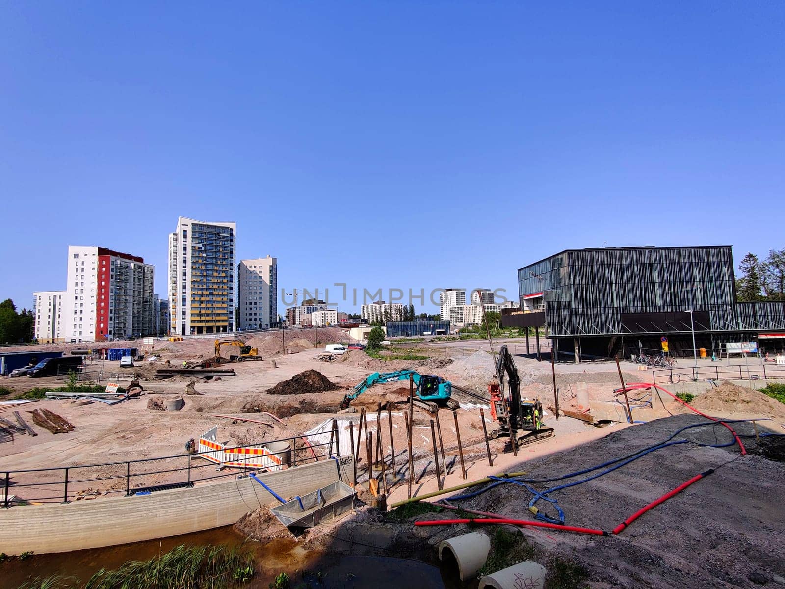 Espoo, Finland - JUNE 4th, 2025: Meritie construction in the city of Espoo, Finland, Finnoo metro station. Excavators are digging the road. The area is closed with construction barriers