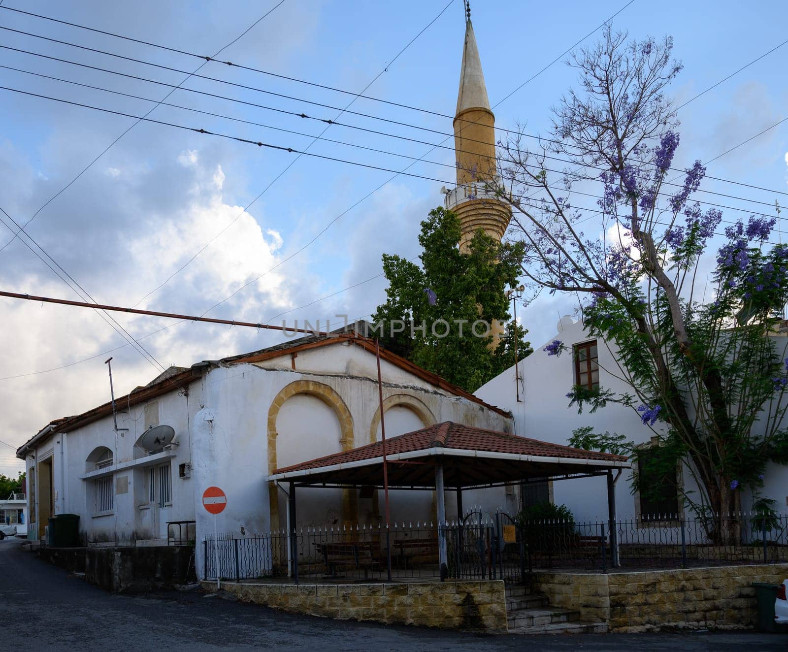 Scenic view of traditional Cypriot houses alongside a tall minaret, showcasing the island’s cultural blend of architecture.