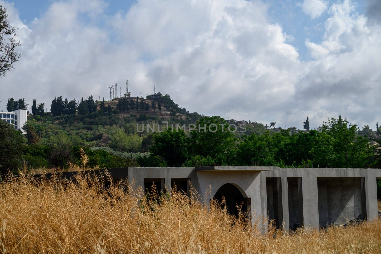 An unfinished residential building stands against a mountainous backdrop featuring the iconic Ataturk silhouette, a symbol seen across Northern Cyprus.