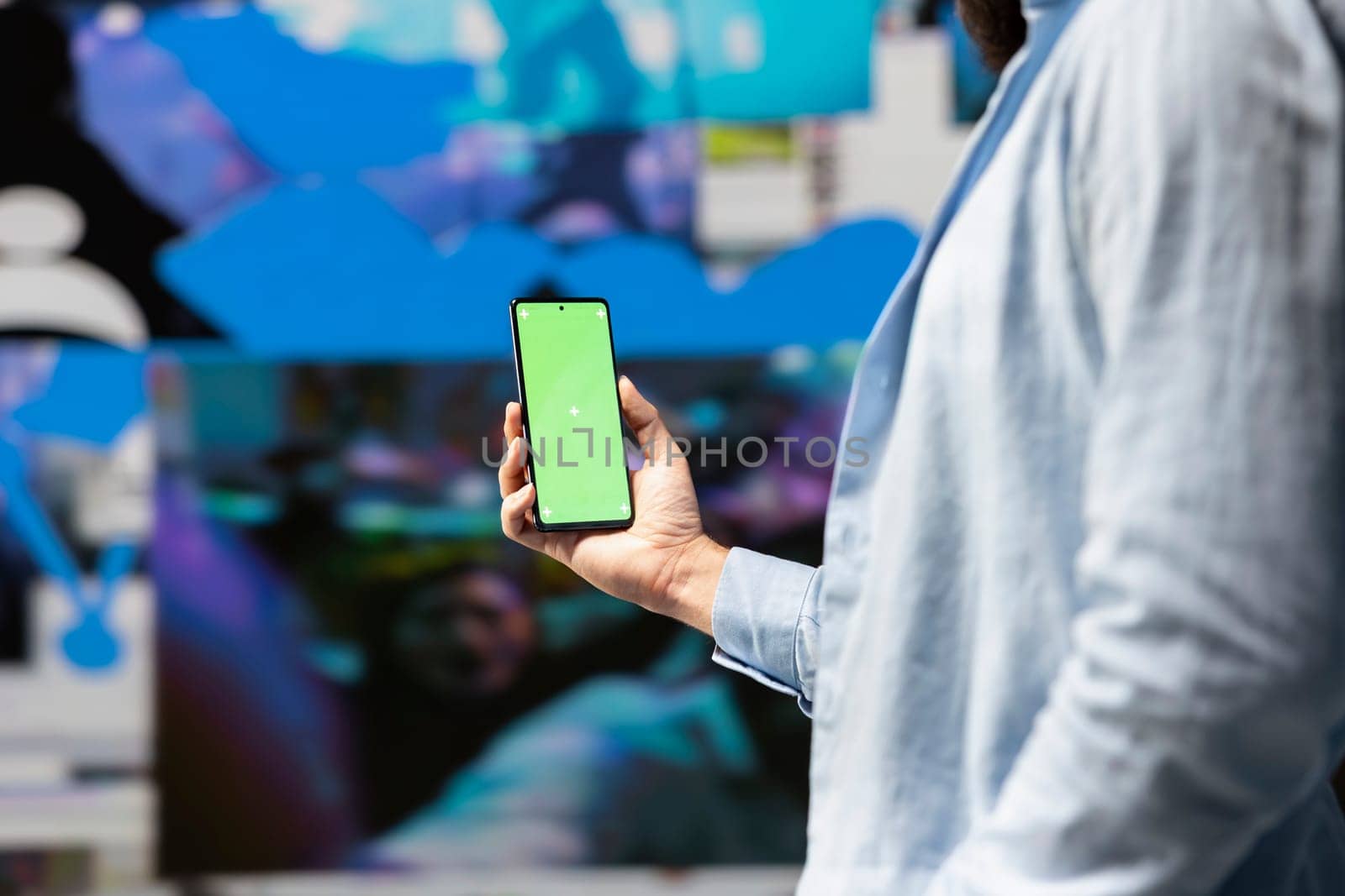 Male influencer holds phone with chroma key screen for online presence, using his imagination and storytelling skills to connect with followers and boost online engagement. Modern web design.