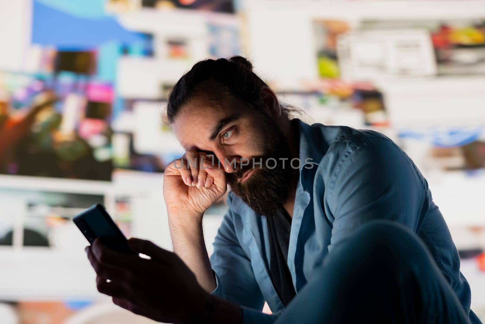 Distressed man suffers from social anxiety damage due to obsessive social media use. Young adult overwhelmed by excessive information and overload or cyberbullying affecting his self esteem.