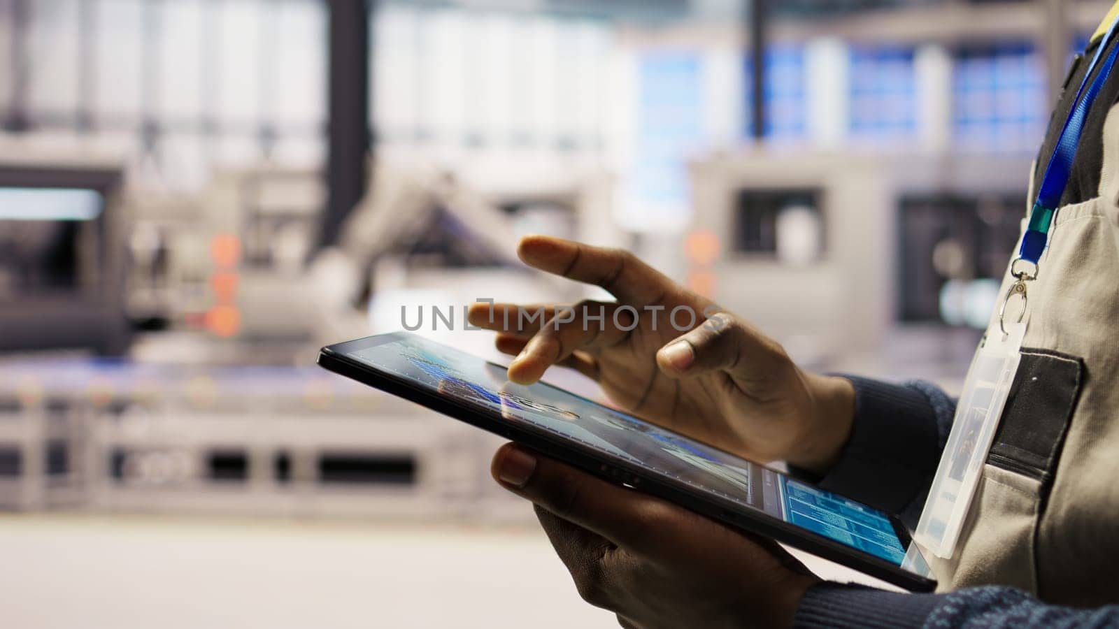 Close up of engineer using tablet to design solar panels factory layouts, utilizing CAD software and simulation tools, optimizing production systems in automated photovoltaics plant, camera A
