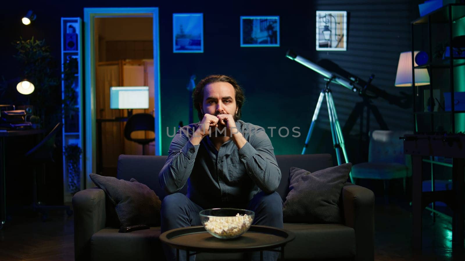 Disappointed supporter watching sports match on live broadcast, upset by team mistake. Annoyed man at home on couch looking at football competition, dejected by chance missed by player