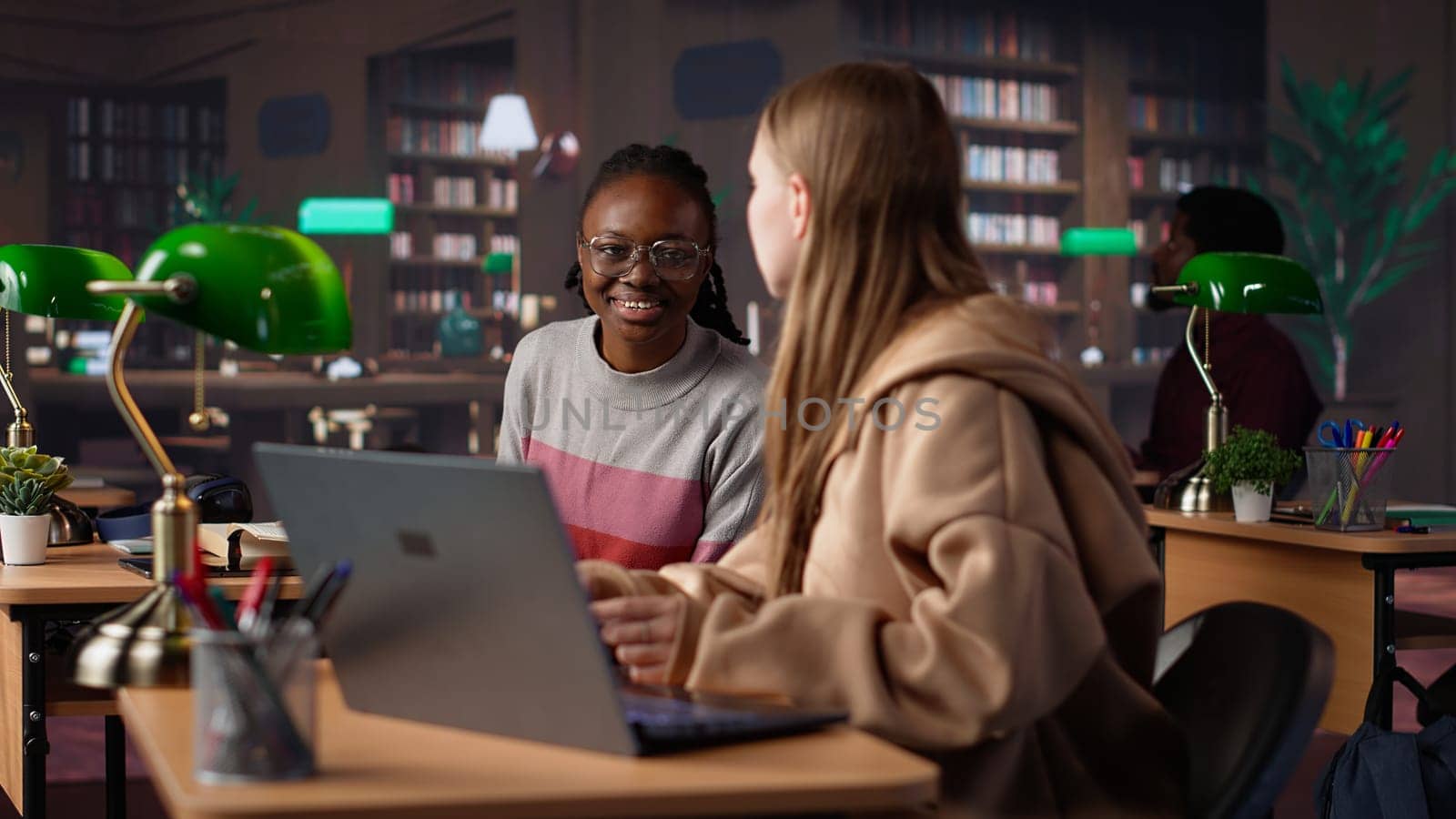 Female student reading and writing detailed notes for an exam, studying political science for upcoming lecture in a library setting at the university. Young adult consults a colleague. Camera A.