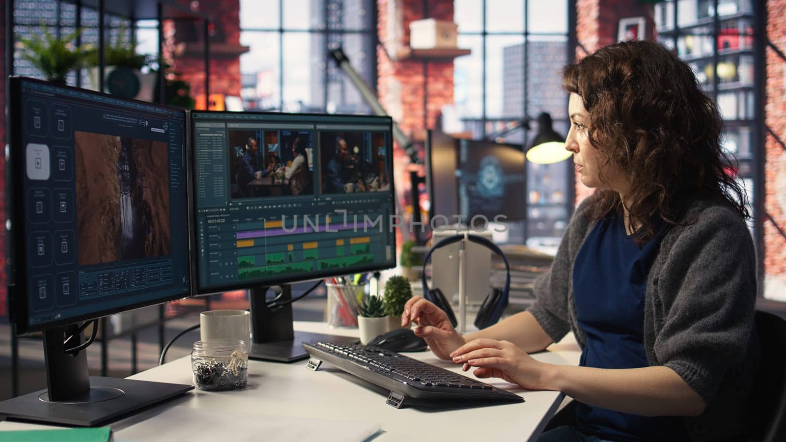 Female videographer working with dual monitors at the creative agency, editing video montage and does color grading for the creative process. Post production to create footage. Camera A.