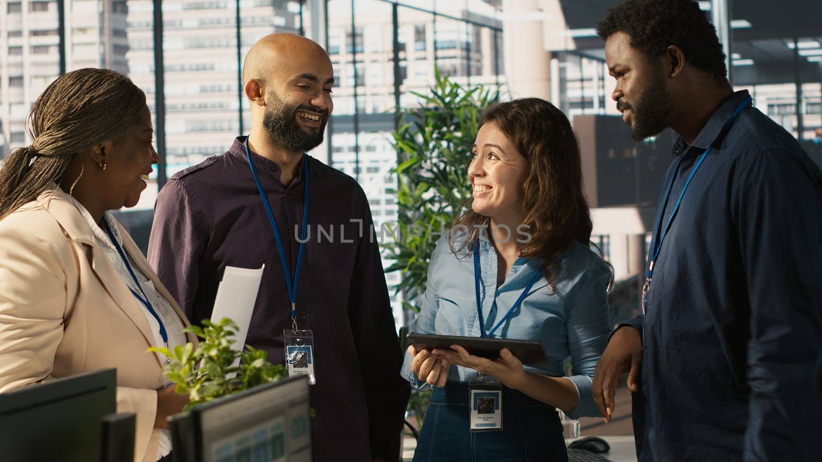 Relaxed multiethnic coworkers in office having fun chatting while reviewing documents, analyzing metrics. Smiling multiracial colleagues talking, working together, looking over paperwork, camera A