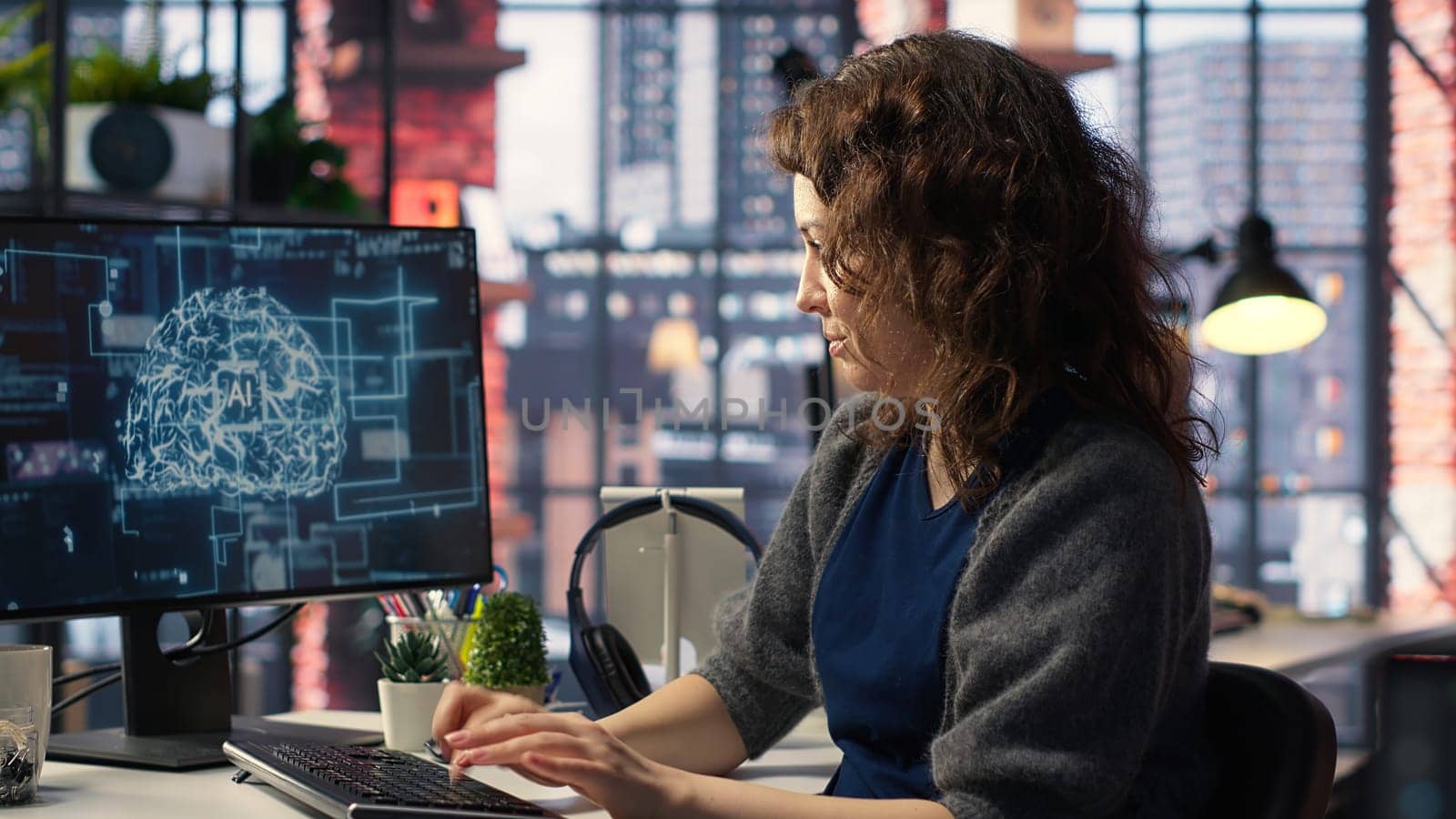 Female system admin doing maintenance on AI brain pc systems, sitting at office desk. Girl works as a software developer with cybernetics and algorithms for machine learning. Camera B.