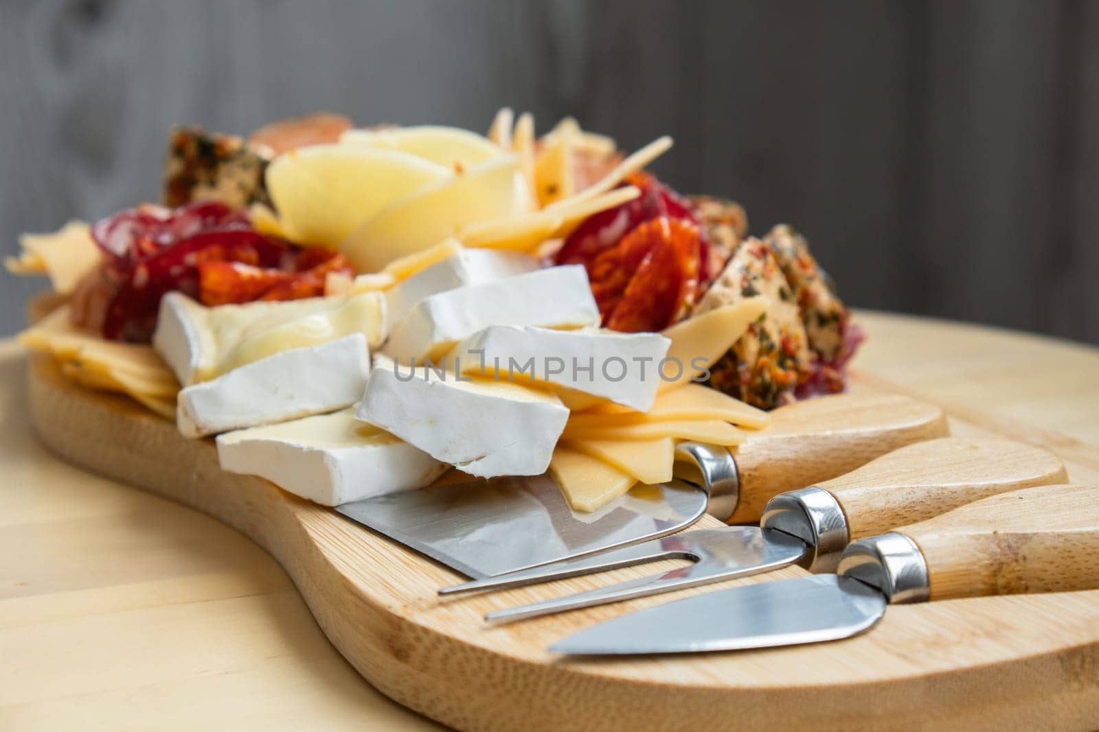 Cheese and meat charcuterie board. Gift present idea, dinner lunch plate. Minimal effort visually pleasing snacks. Simple meal preparation with special cheese knives. Wooden board