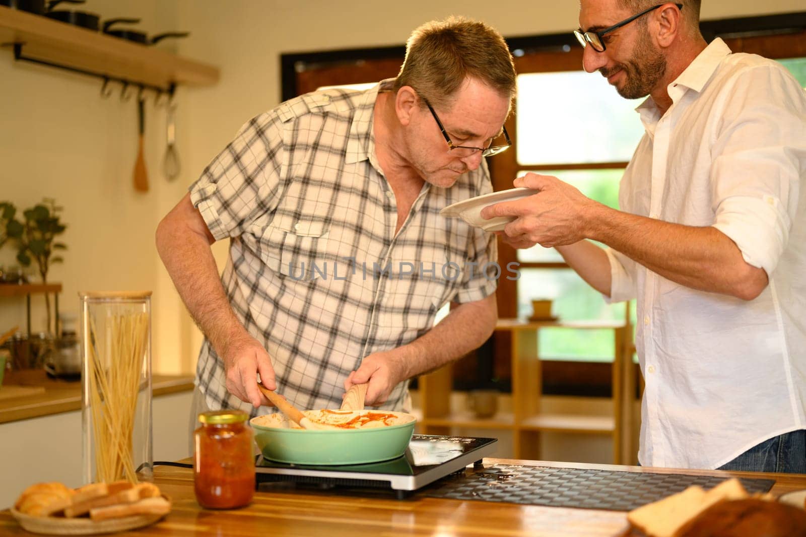 Father and son enjoy cooking a fresh homemade dish in a home kitchen. Father day concept.