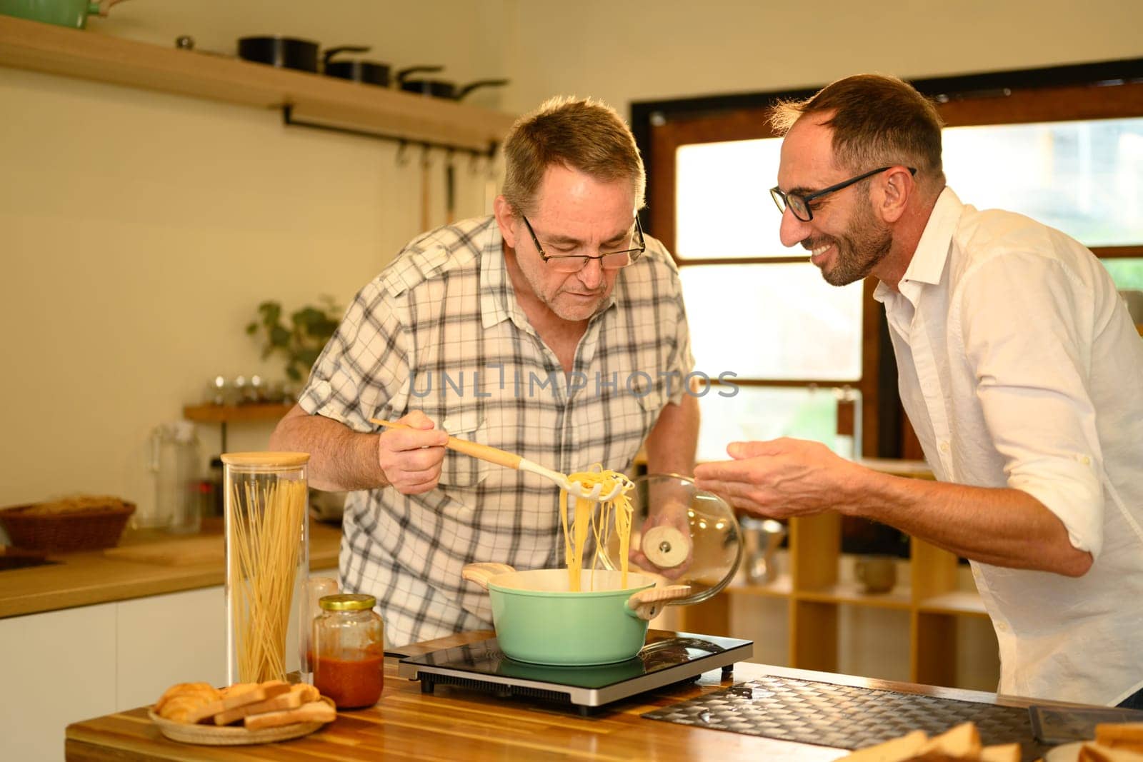 Father and son enjoy cooking a fresh homemade dish in a home kitchen. Father day concept.